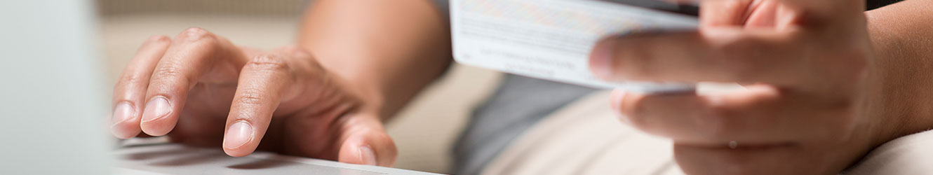 Close up of person using credit card and computer